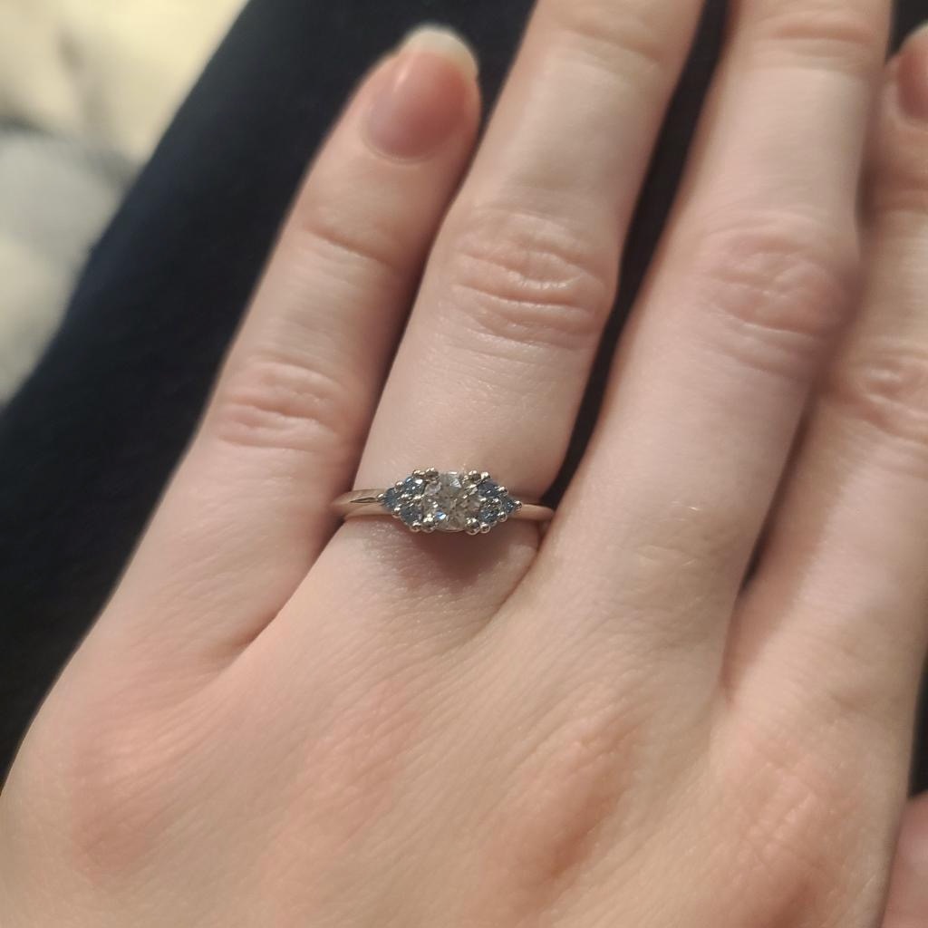 A diamond ring with side diamonds on a woman's left hand
